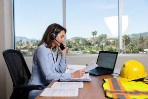 photo of an insurance adjuster reviewing California workers’ compensation claim documents and speaking with an injured worker on the phone in a sunny Southern California office – illustrating the key role of adjusters in workers comp cases for Laguna Law Firm clients in Mission Viejo and Orange County.