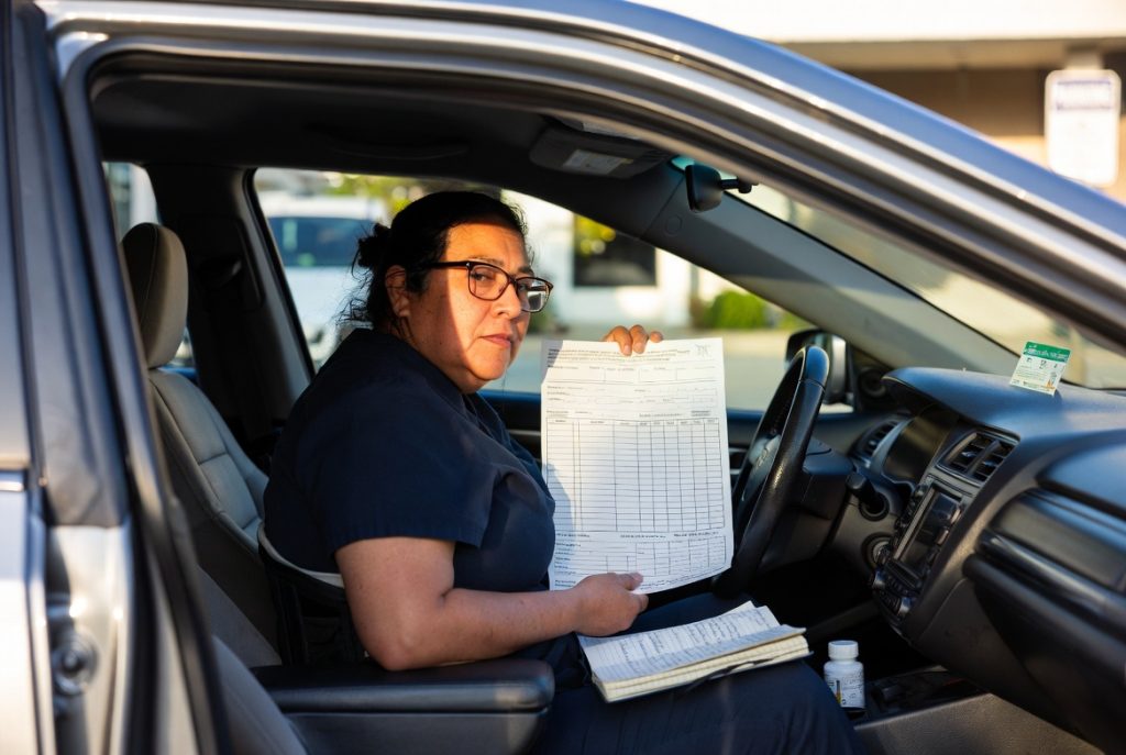 Injured worker reviewing mileage reimbursement form for California workers' compensation medical appointments in 2026 while sitting in her car after a doctor visit