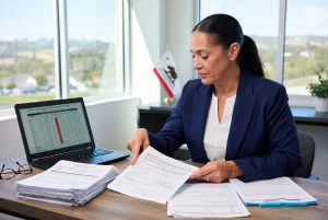 Ultra-realistic photo of an injured California construction worker sitting on a bench reviewing his workers’ compensation claim forms, wearing back brace, knee brace, and shoulder tape at a job site with palm trees in the background